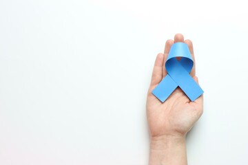 Blue ribbon above a Woman’s hand in a white background and copy space in the left