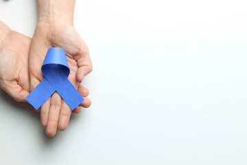 Blue ribbon above a Woman’s hands in a white background and copy space in the left