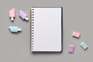 Notebook with markers and erasers on grey background