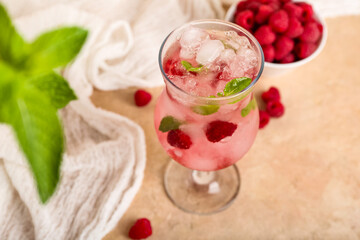 Glass of fresh raspberry mojito and bowl with berries on pink background