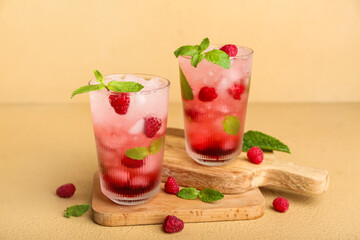 Wooden boards with glasses of fresh raspberry mojito on yellow background