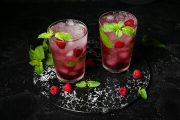 Board with glasses of fresh raspberry mojito on black background
