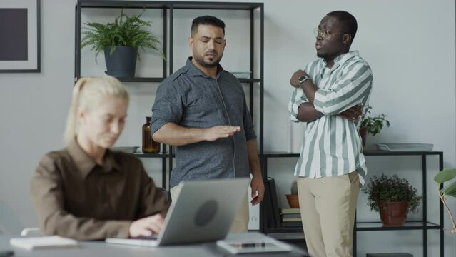 African American and Middle Eastern men standing behind their female co-worker slandering her on purposeAfrican American and Middle Eastern men standing behind their female co-worker slandering her on