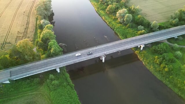 A passenger car overtaking another car on a road bridge on the San River in the evening