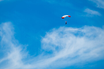 Parachutist with a white and red parachute against the blue sky