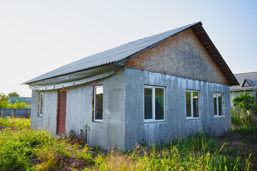 An abandoned unfinished house on a grassy plot. 