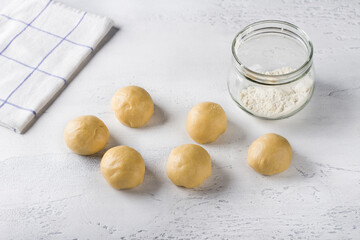 Cooking homemade buns. Raw pieces of dough or buns and a jar of flour on a light blue background