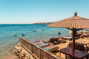 Sun beds on the beach in Dahab with divers in the water, Southern sinai, Egypt
