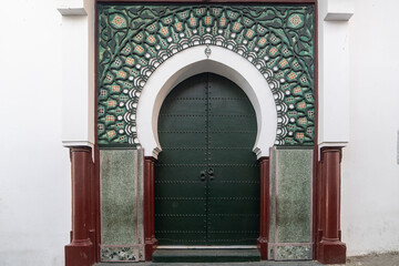 An ornamented gate in moorish style with geometric islamic patterns and  house painted white at Ksbah, Ancient Medina, Tangier, Morocco
