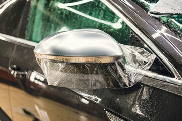 Obraz premium The process of installing PPF on the side mirror. Car wrapping close-up.