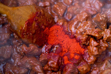 Traditional goulash soup is cooking in the a cauldron.