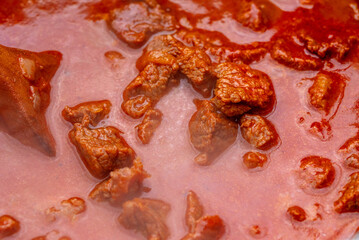 Traditional goulash soup is cooking in the a cauldron.