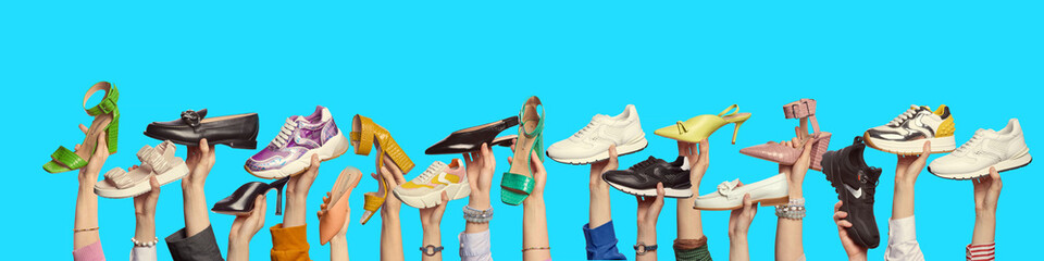 Multiple hands holding trendy shoes of different colors and styles on isolated blue background with...