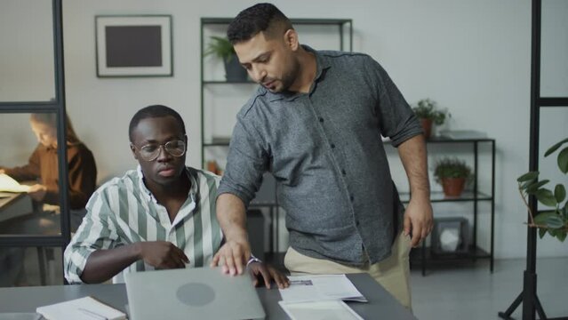 Impudent Middle Eastern man disturbing his African American subordinate and making him do extra workImpudent Middle Eastern man disturbing his African American subordinate and making him do extra work