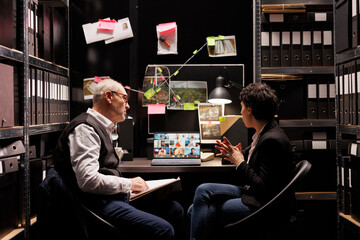 Investigators explaining crime scene evidence to criminology team during online videocall meeting conference. Private detectives working late at night at criminal case in arhive room