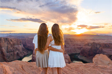 Happy girls on the edge of the cliff at Horseshoe Band Canyon in Paje, Arizona. Adventure and...