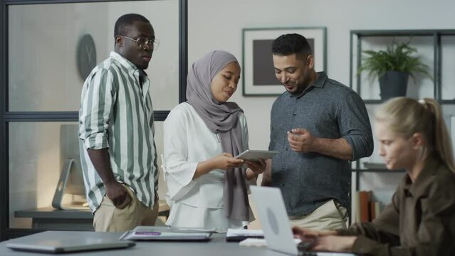 Selective focus shot of envious office workers intentionally badmouthing and spreading gossips about their successful colleague