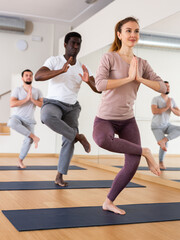 Obraz premium Multiethnic group of people exercising yoga poses in gym.