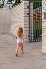Back view of little girl running in front of the entrance to the house