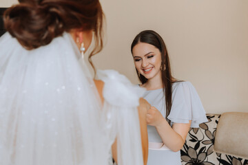 Portrait of the bride with her friends. The bride is posing in a voluminous white dress and her beautiful friends in gray evening dresses. Brunettes Open shoulders. Morning of the bride.