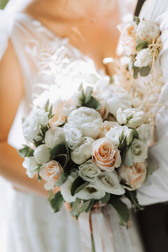 A wedding bouquet of white roses in the hands of the bride. Close-up photo of the bouquet