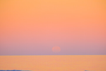 Sturgeon Supermoon over the sea with a pink palette background, full pink moon