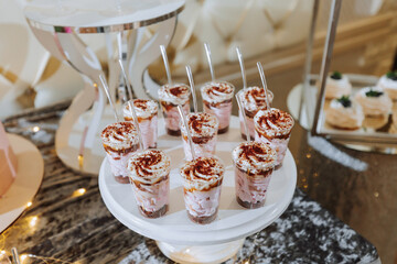 A delicious wedding. White cake decorated with flowers. Candy bar for a banquet. Celebration concept. Fashionable desserts. Table with sweets, candies. Fruits