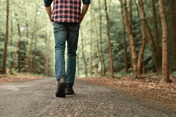 Man walking on sunlit trail in autumn forest enjoying peaceful walk in nature 