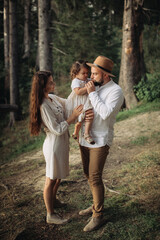 Happy family with little daughter in the forest