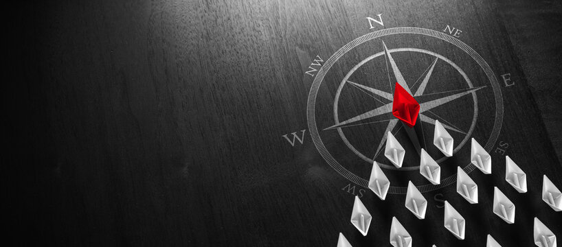 Red Paper Boat Leading A Fleet Of Small White Boats With Compass Icon On Black Modern Wooden Table - Leadership Concept
