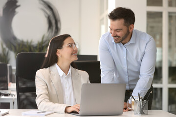 Colleagues working on laptop at desk in office
