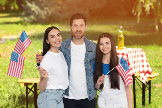 4th of July - Independence day of America. Happy family with national flags of United States having picnic in park