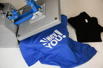 Printing logo. Heat press with t-shirts on white table