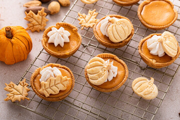 Mini pumpkin pies for Thanksgiving with leaves and pumpkin garnishes and whipped cream