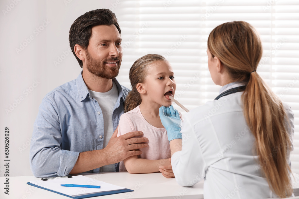 Canvas Prints doctor examining girl`s oral cavity with tongue depressor near her father indoors