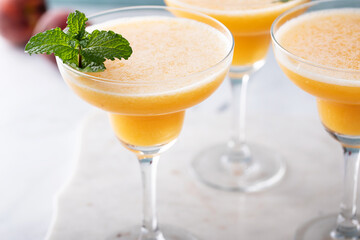 Frozen peach margaritas in three glasses with mint