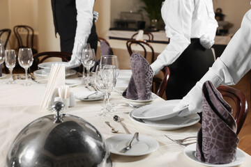 People setting table during professional butler courses in restaurant, closeup