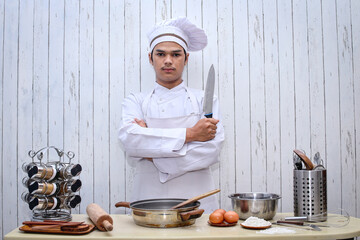 Portrait of male chef in white toque and apron posing with a knife. Cooking and culinary concept.