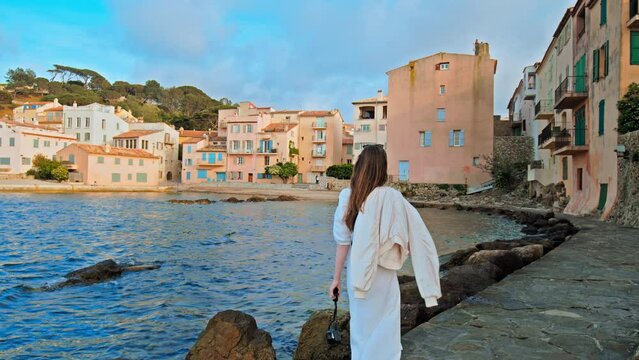 Beautiful girl enjoys the sunset in Cote d'Azur, a coastal town on the French Riviera. Young woman explores historical colorful Old Town of Saint Tropez, a popular resort on the Mediterranean Sea. 