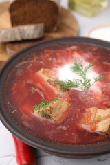 Tasty borscht with sour cream in bowl on table, closeup