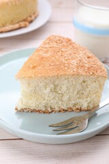 Piece of tasty sponge cake on white wooden table, closeup