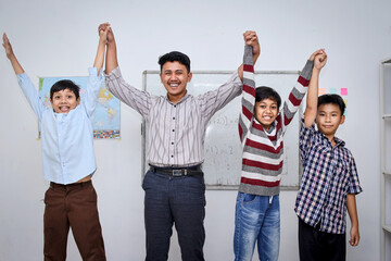 Portrait of teacher and students raising their hands together celebrate teacher's day