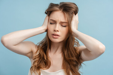 Closeup, tired woman with long hair with headache holding her head isolated on blue background