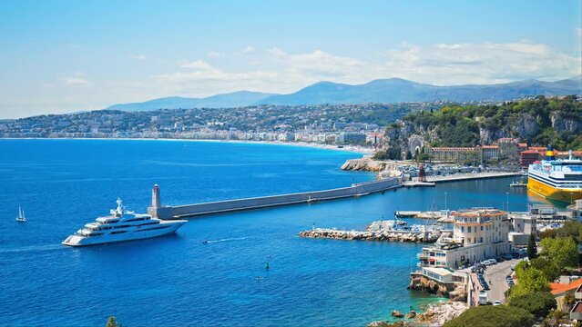 Stunning view of the Mediterranean Sea with the lighthouse in the harbor in Nice. Landscape with a luxury yacht approaching the sea shore in South of France, French Riviera.
