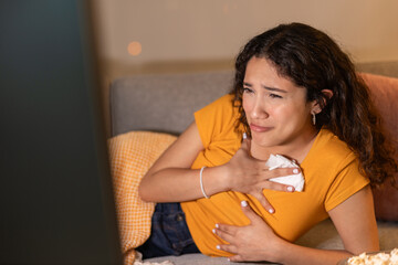 Emotional young woman crying while watching a movie on TV