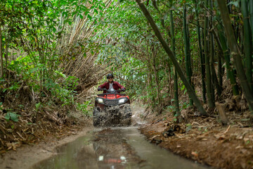 Asian guy having fun while driving an atv in the jungle alone. Drive through water in the deep...