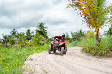 Happy young couple in nature on a quad bike. Young man enjoying a quad bike ride in countryside. Man driving and woman enjoying the ride with her hands raised on a summer day. © 2B