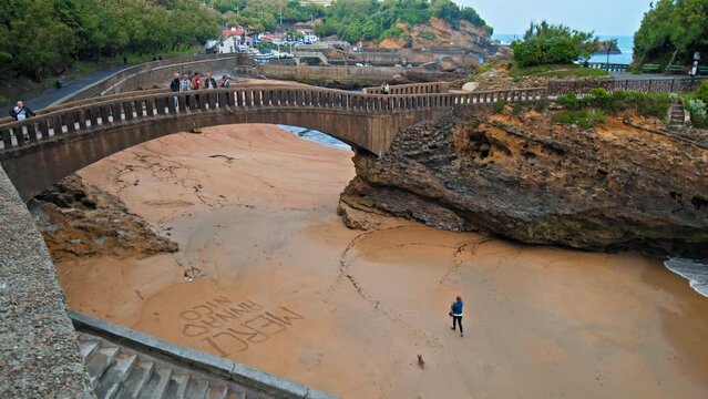 Basta Rock iconic bridge by Rocher de la Vierge in Biarritz town city, France. People tourists walk by a Beautiful rocky bridge on the seashore of the elegant royal town Biarritz.