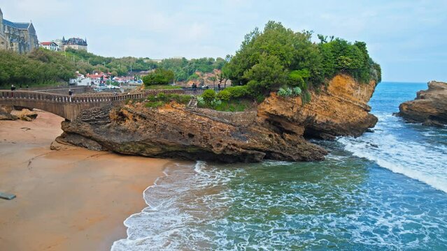 Basta Rock iconic bridge by Rocher de la Vierge in Biarritz town city, France. People tourists walk by a Beautiful rocky bridge on the seashore of the elegant royal town Biarritz.