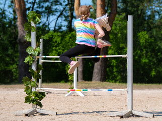 Girl jumping on hobby horse. Champion. Horse sport. Summer light. Green outdoor trees background....